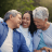Adult daughter sits between her parents on a bench outdoors, smiling and embracing them as they laugh together, symbolizing a loved one who may one day serve as a life insurance beneficiary.